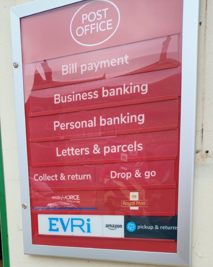 The Post Office services sign in the Wootton shop window: bill payment, business banking, personal banking, letters and parcels, collect and return, drop and go